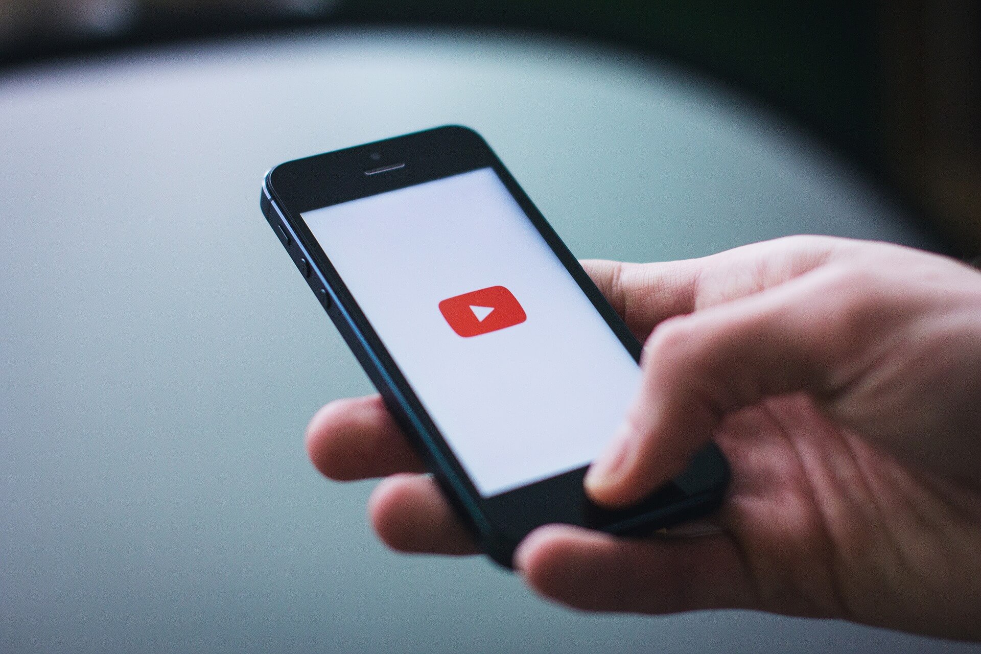 hand holding phone with youtube play icon